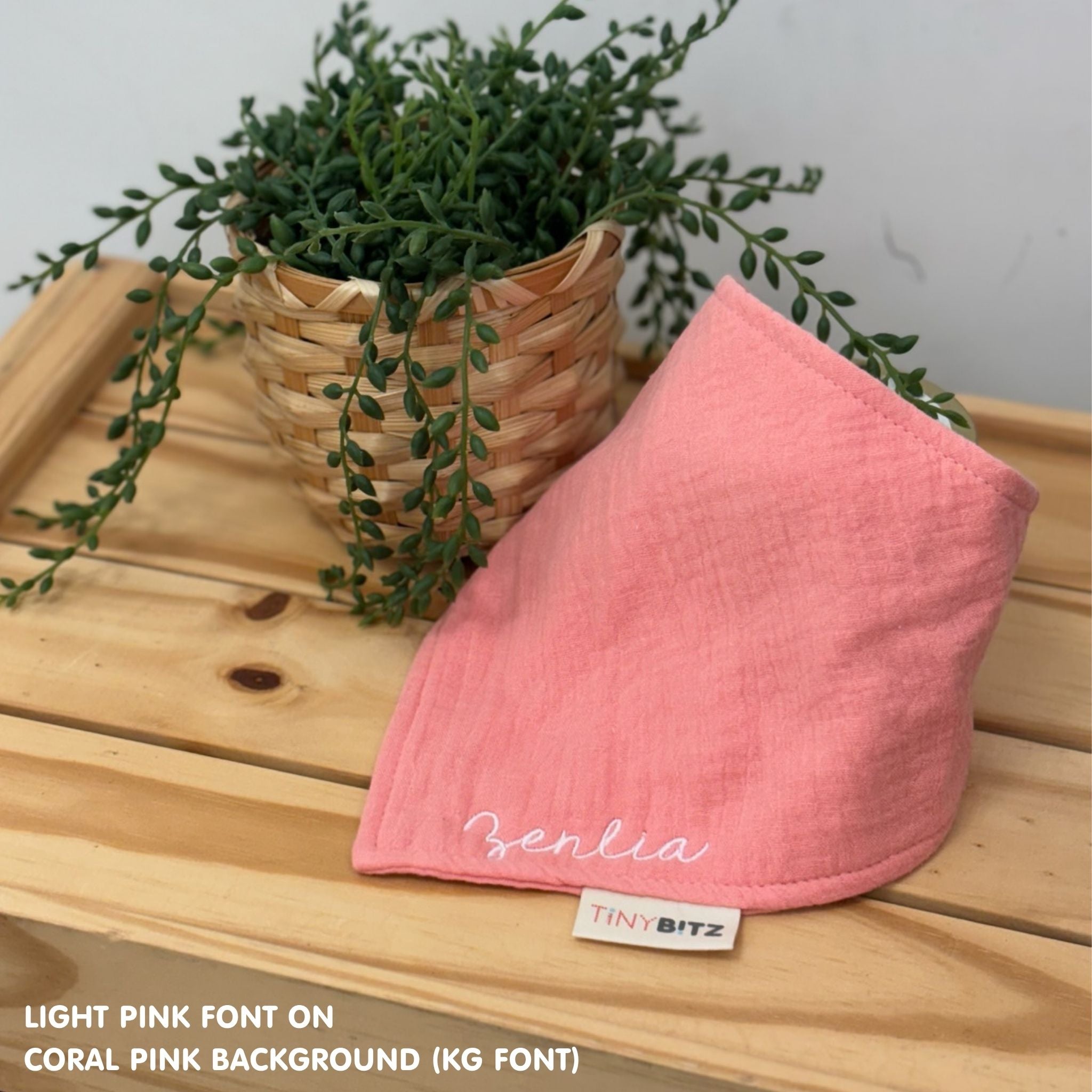 Personalized coral pink organic muslin bib with custom name embroidery, perfect for baby gifts and keepsake accessories.