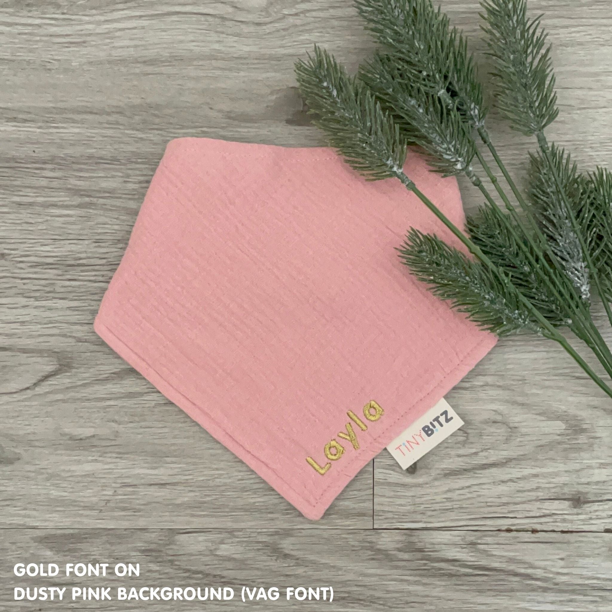 Personalized dusty pink organic muslin bib with custom name embroidery, perfect for baby gifts and keepsake accessories.