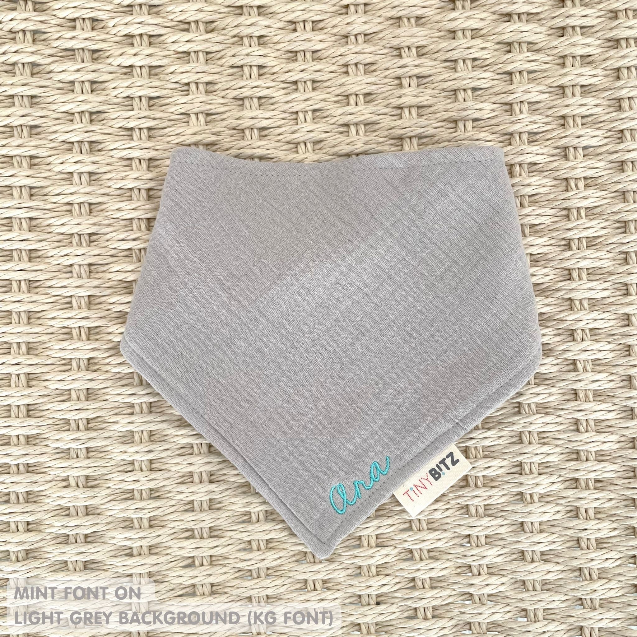 Organic personalised bib for babies in light grey, featuring baby name in script font, unique baby gift idea by TinyBitz.