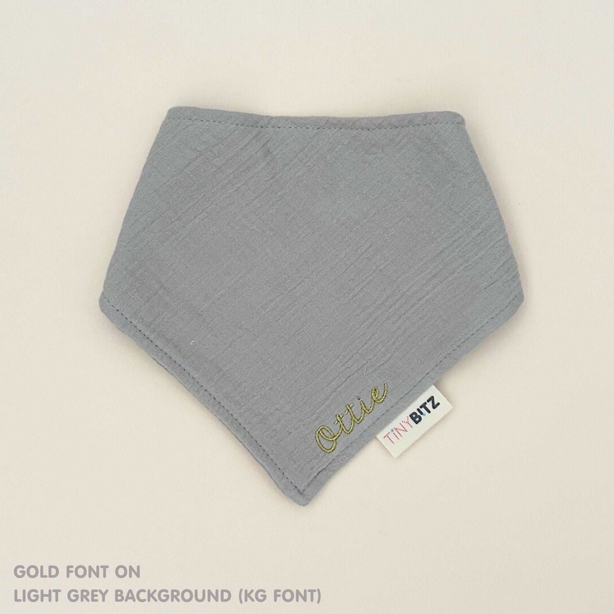 Organic personalised bib for babies in light grey, featuring baby name in script font, unique baby gift idea by TinyBitz.