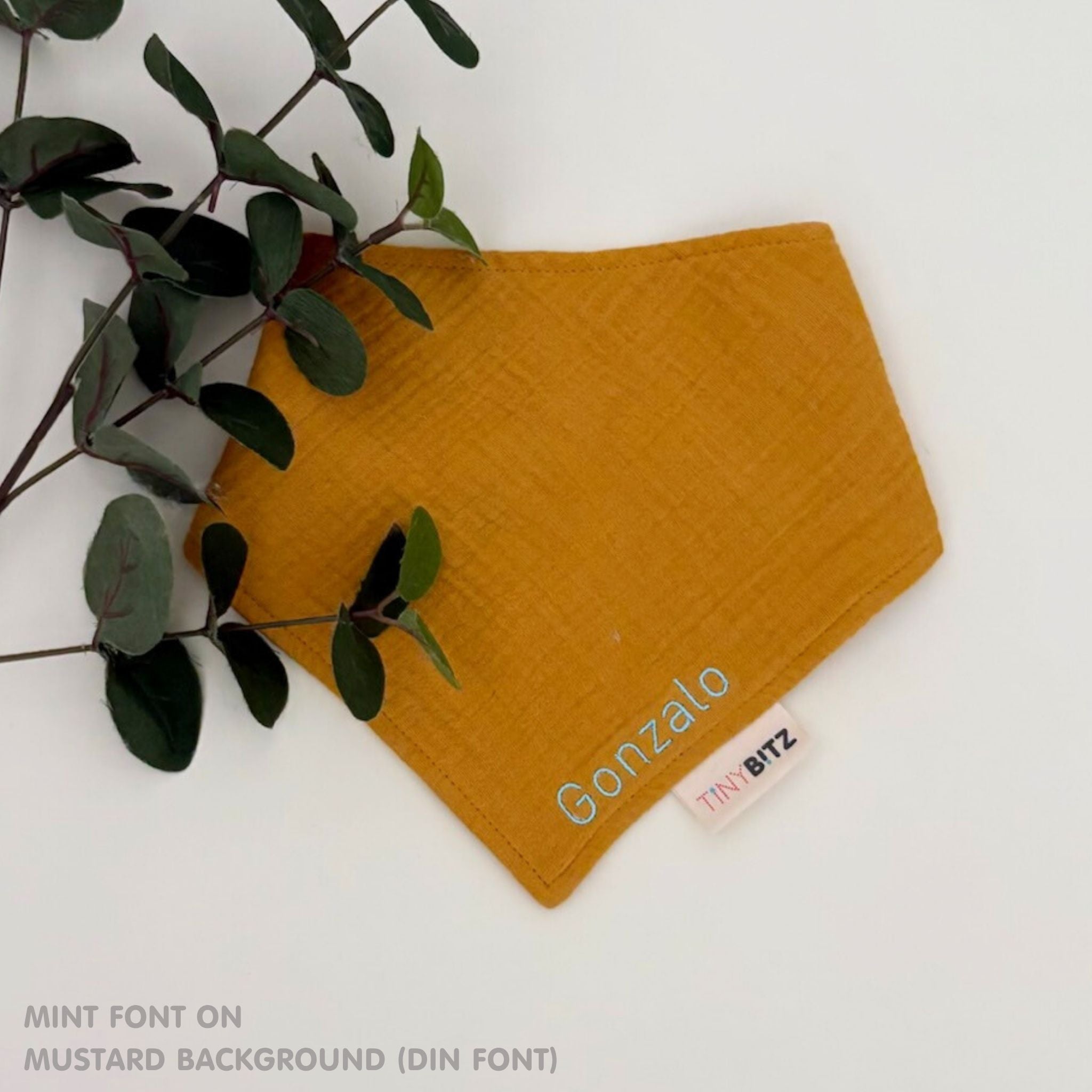 Organic cotton baby bib with name stitched on mustard fabric, personalised baby gifts by TinyBitz.
