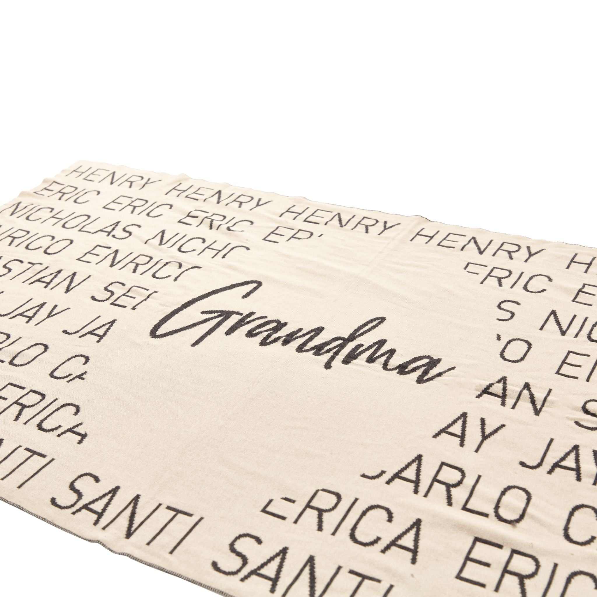 Custom blanket with grandma/grandpa's name knitted in the centre, surrounded by their kids and grandkid's names, made by TinyBitz.