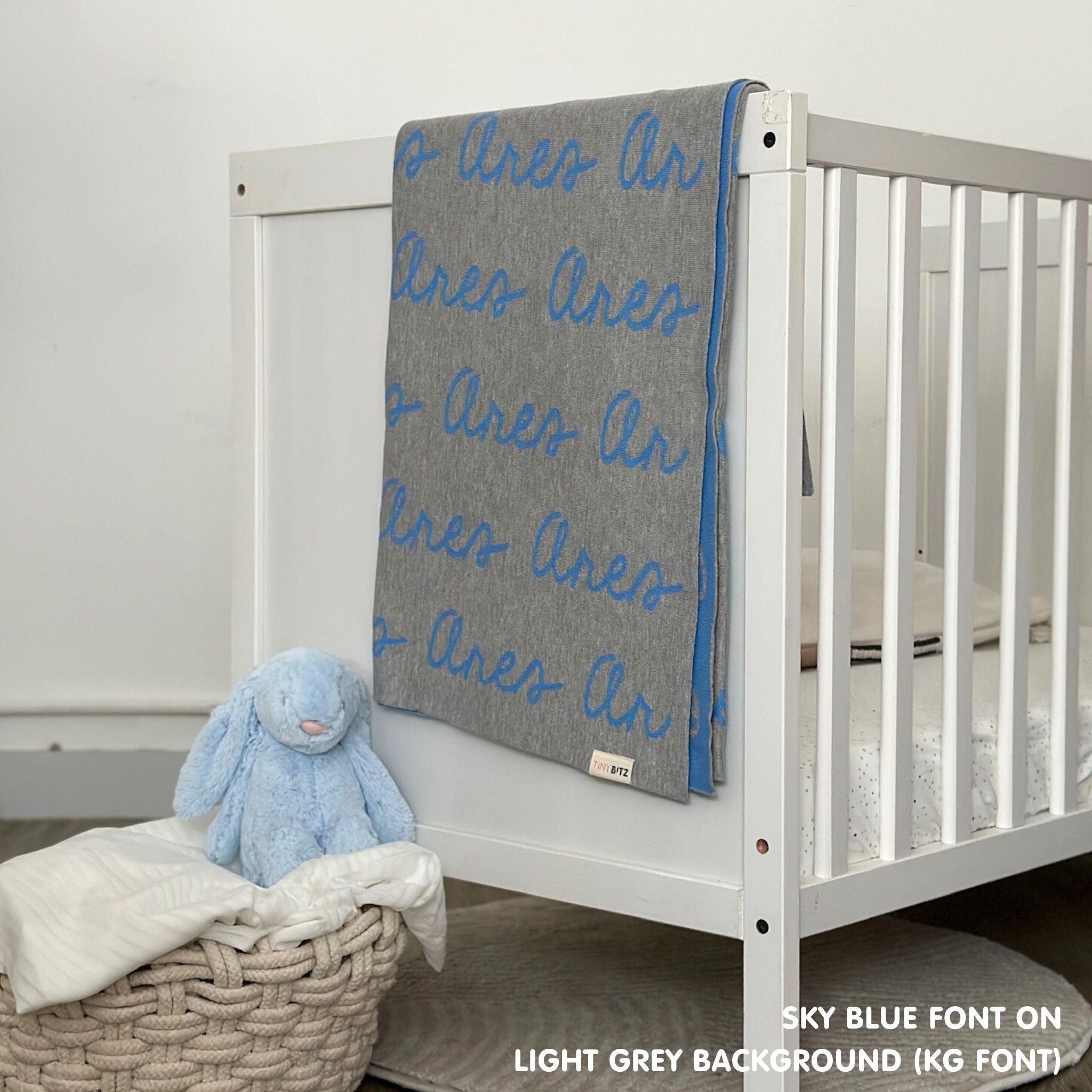 Cotton baby blanket with baby's name knitted in light grey and sky blue, made by TinyBitz.