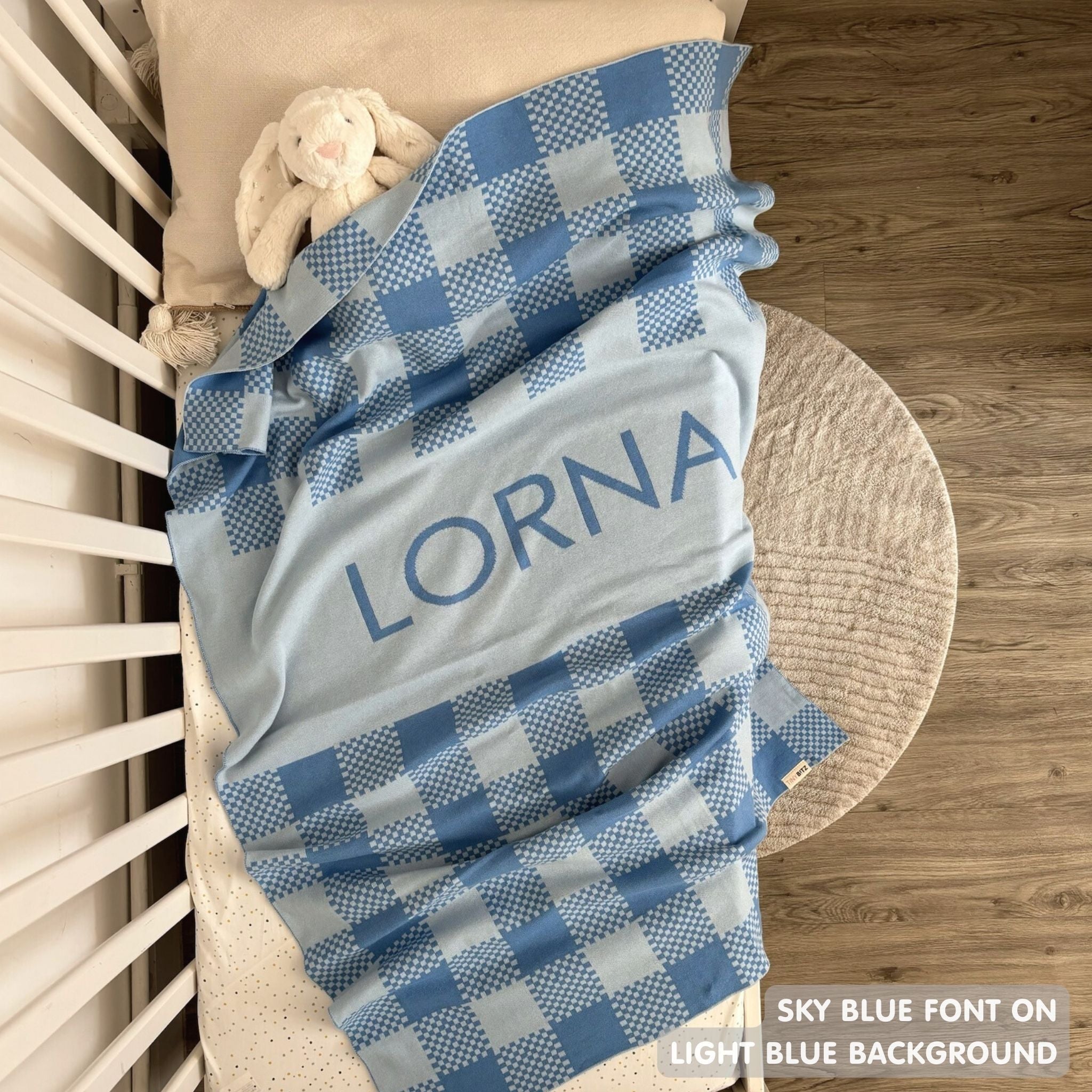 Cotton baby blanket with baby's name, knitted in light blue and sky blue with a check pattern, made by TinyBitz.