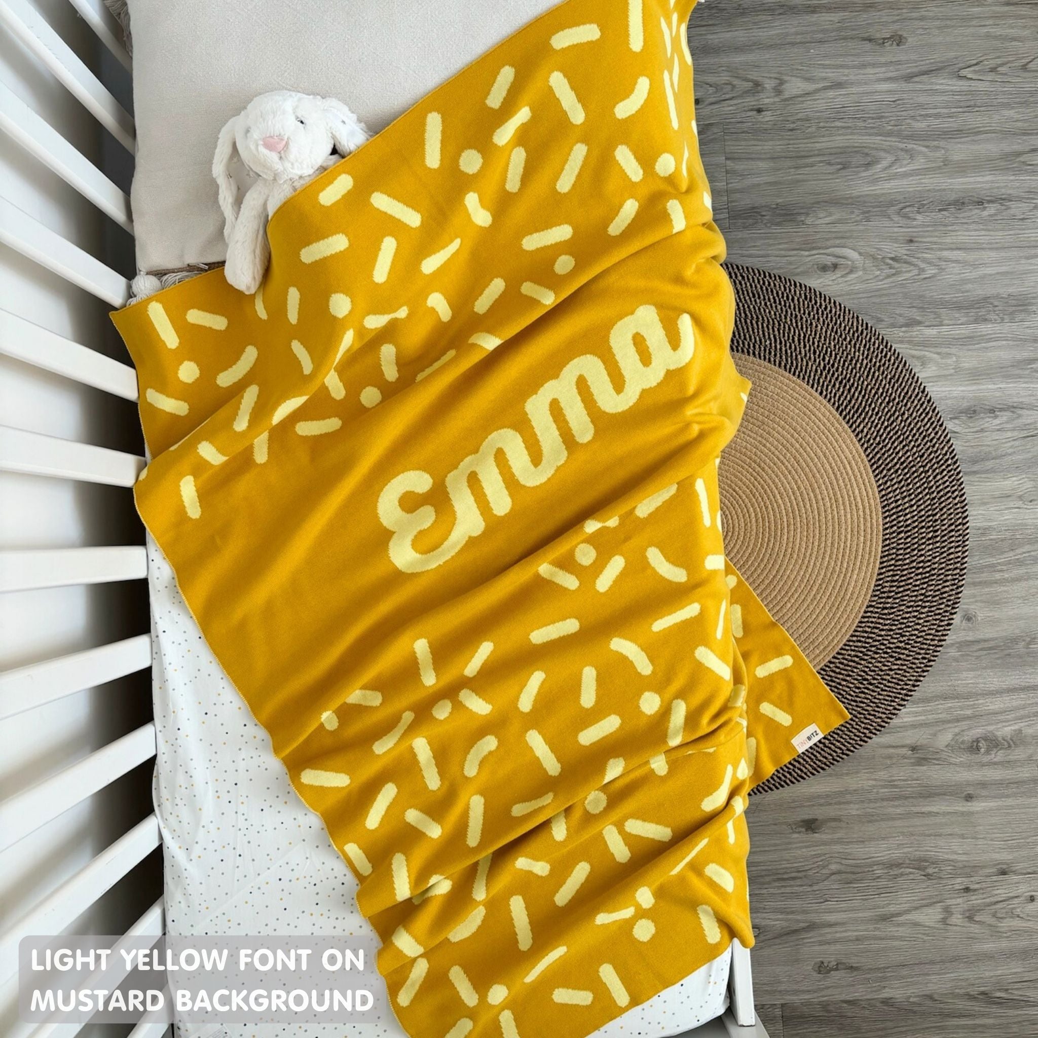 Knitted baby blanket in mustard and light yellow with a confetti pattern, customised with baby's name, made by TinyBitz.