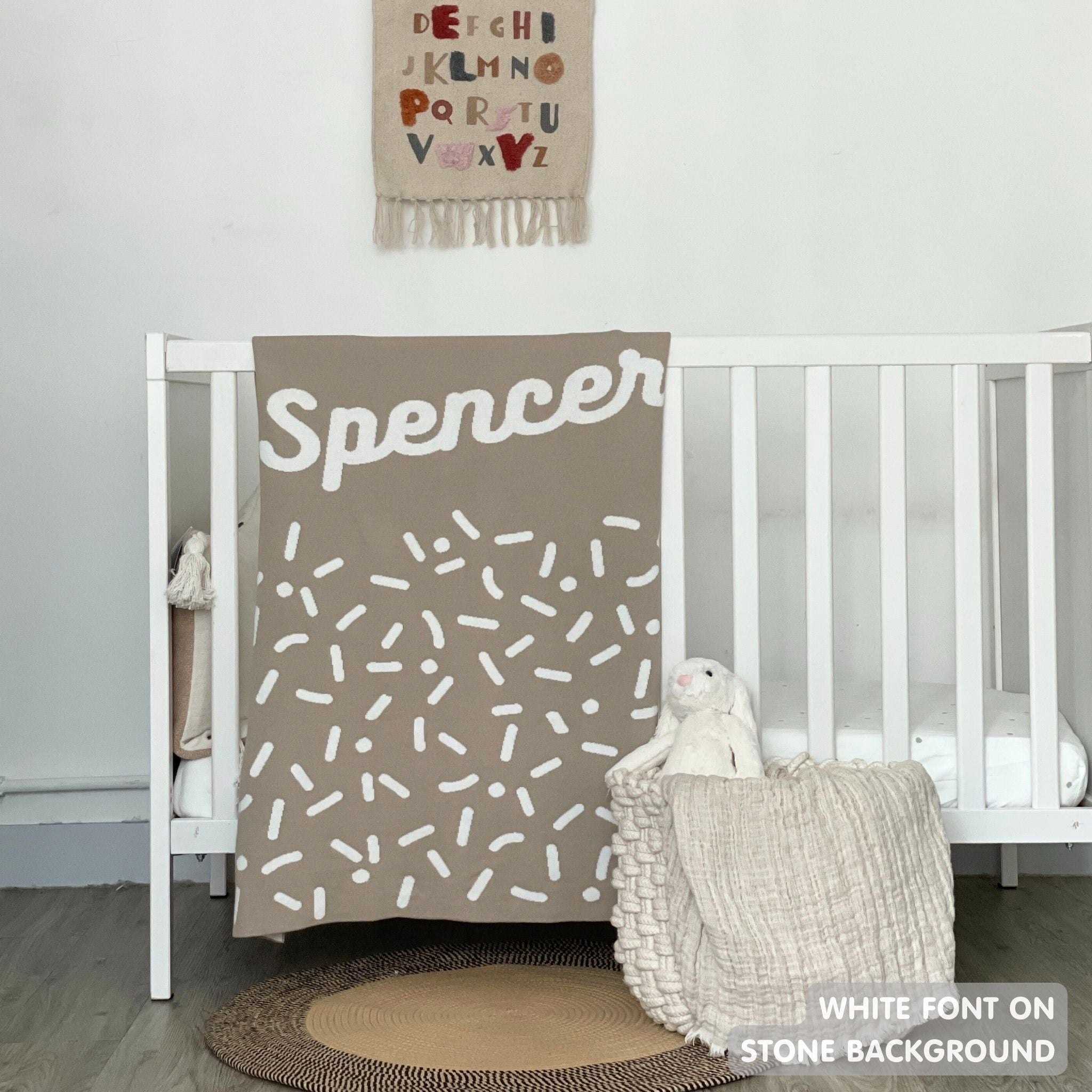 Knitted baby blanket in stone and white with a confetti pattern, customised with baby's name, made by TinyBitz.