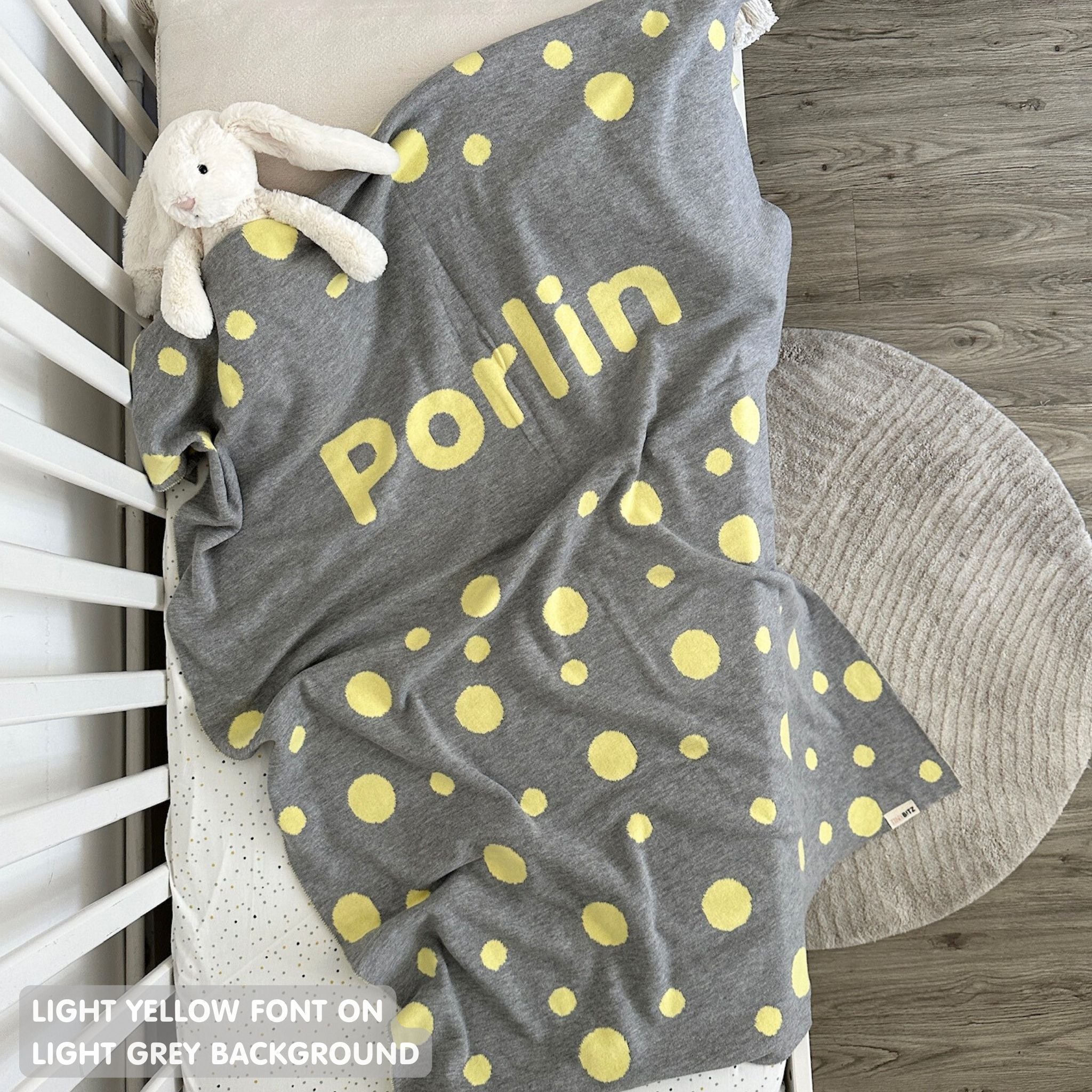 Knitted baby blanket in light grey and light yellow with a dot pattern, customised with baby's name, made by TinyBitz.