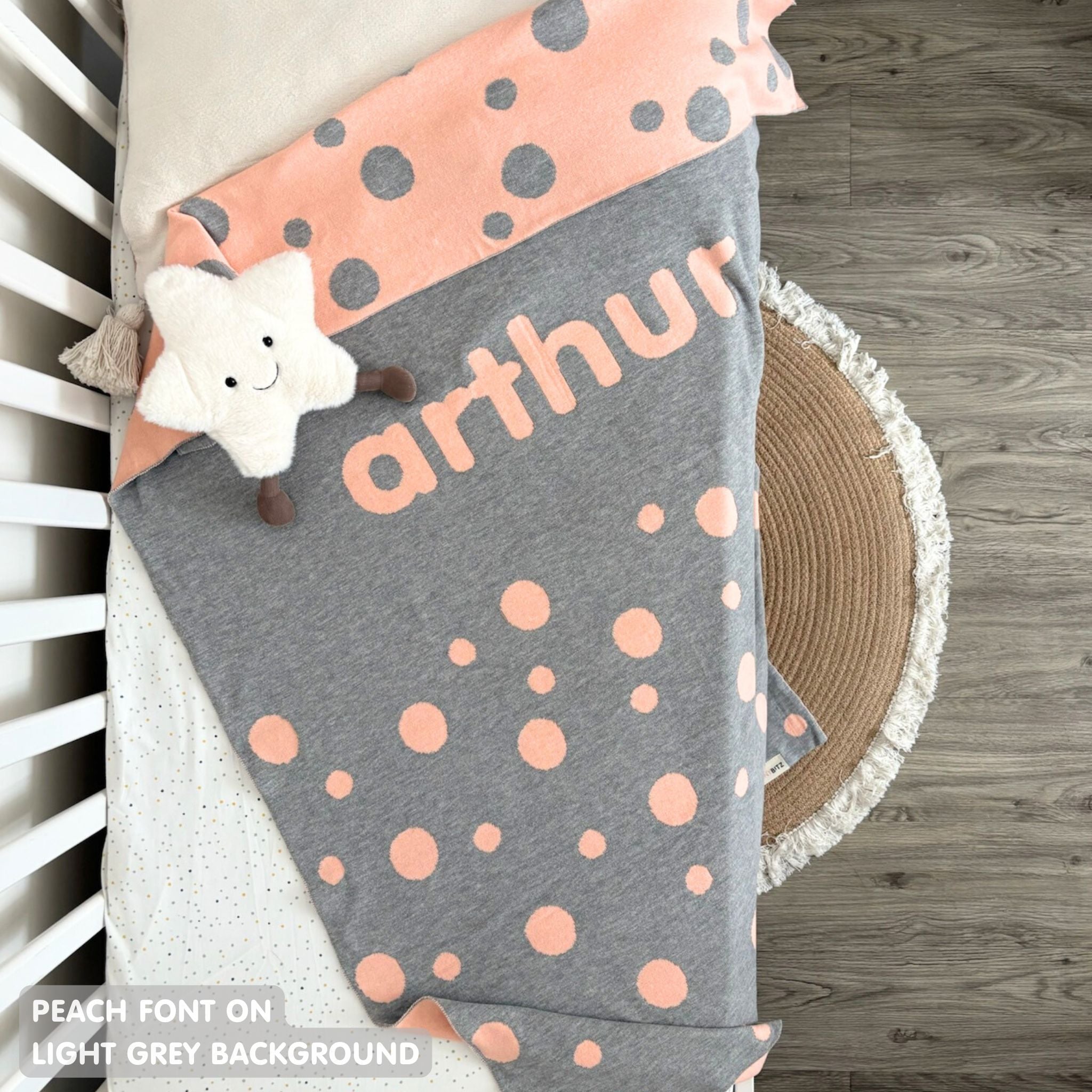 Knitted baby blanket in light grey and peach with a dot pattern, customised with baby's name 'arthur', made by TinyBitz.