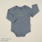 Neutral-tone personalised baby onesie featuring custom name, made-to-order newborn gift by TinyBitz.