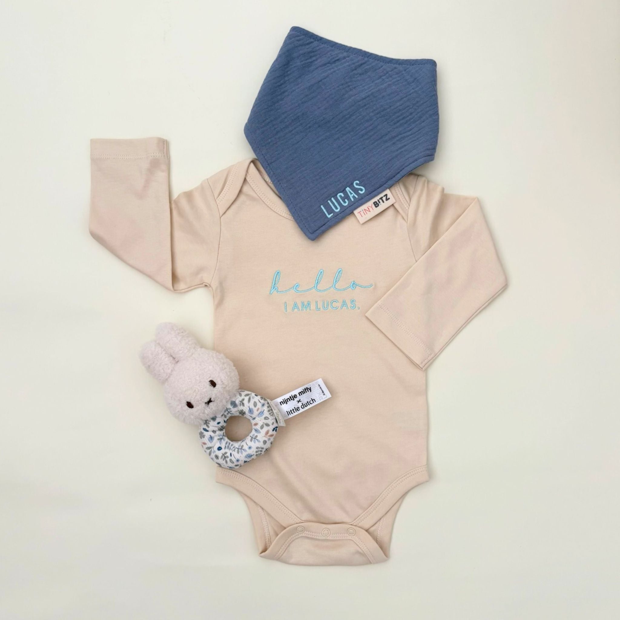 Personalised baby gift set with embroidered onesie, muslin bib, and floral Miffy rattle toy, all neatly packed in a pastel gift box for newborn gifting.