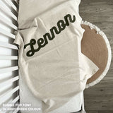 Knitted baby blanket in cream and army green with a confetti pattern, customised with baby's name, made by TinyBitz.