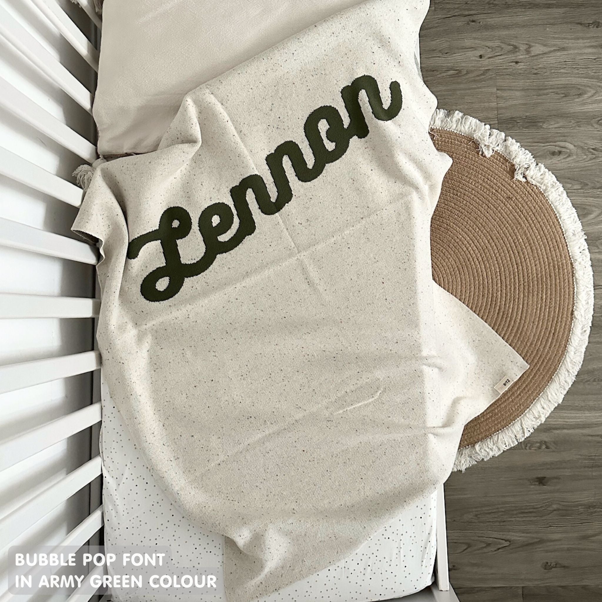 Knitted baby blanket in cream and army green with a confetti pattern, customised with baby's name, made by TinyBitz.