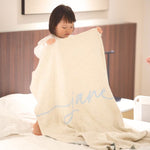 Knitted baby blanket in cream and light blue with a confetti pattern, customised with baby's name, made by TinyBitz.