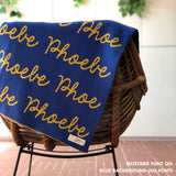 Custom name blanket in blue and mustard draped over a chair makes the best personalized home decor.