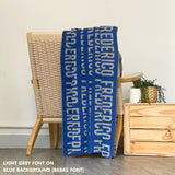 Custom name blanket in navy and light grey draped over a chair makes the best personalized home decor.