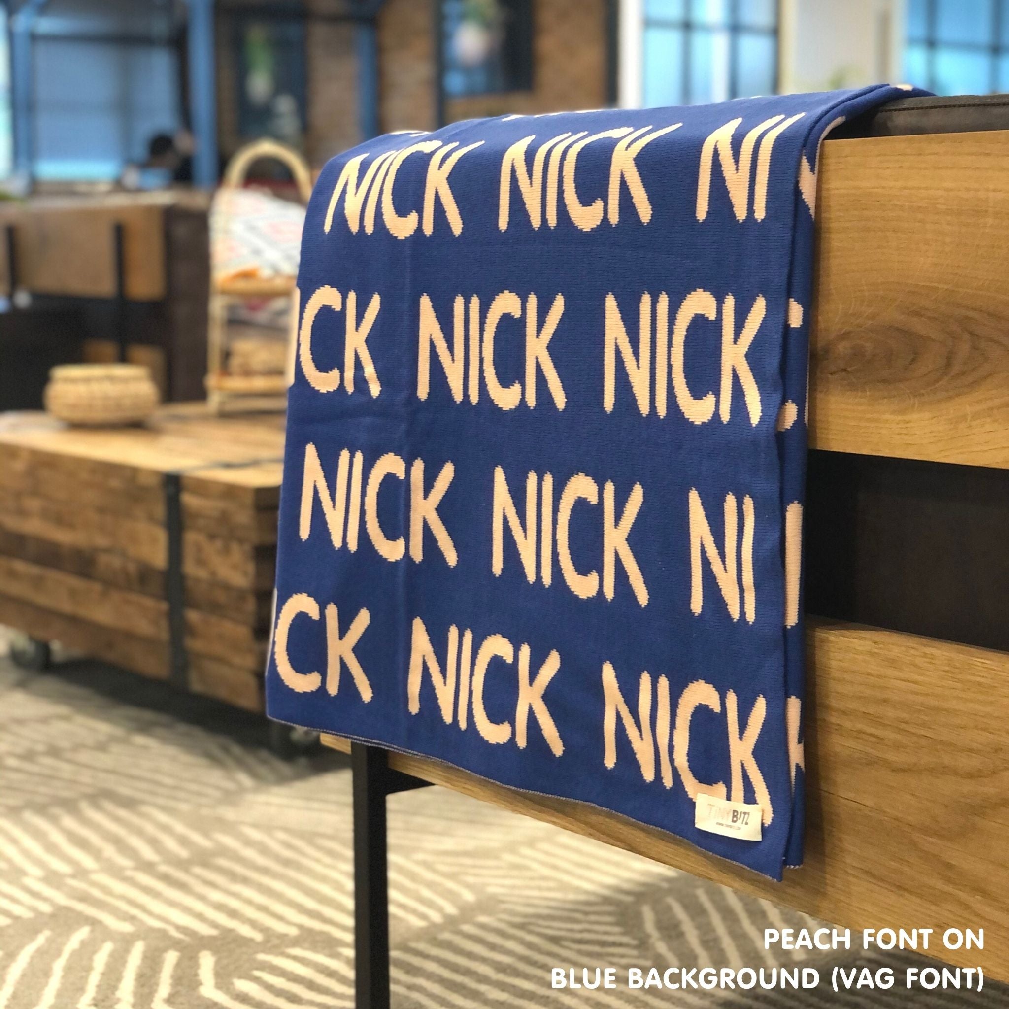 Custom name blanket in blue and peach draped over a chair makes the best personalized home decor.
