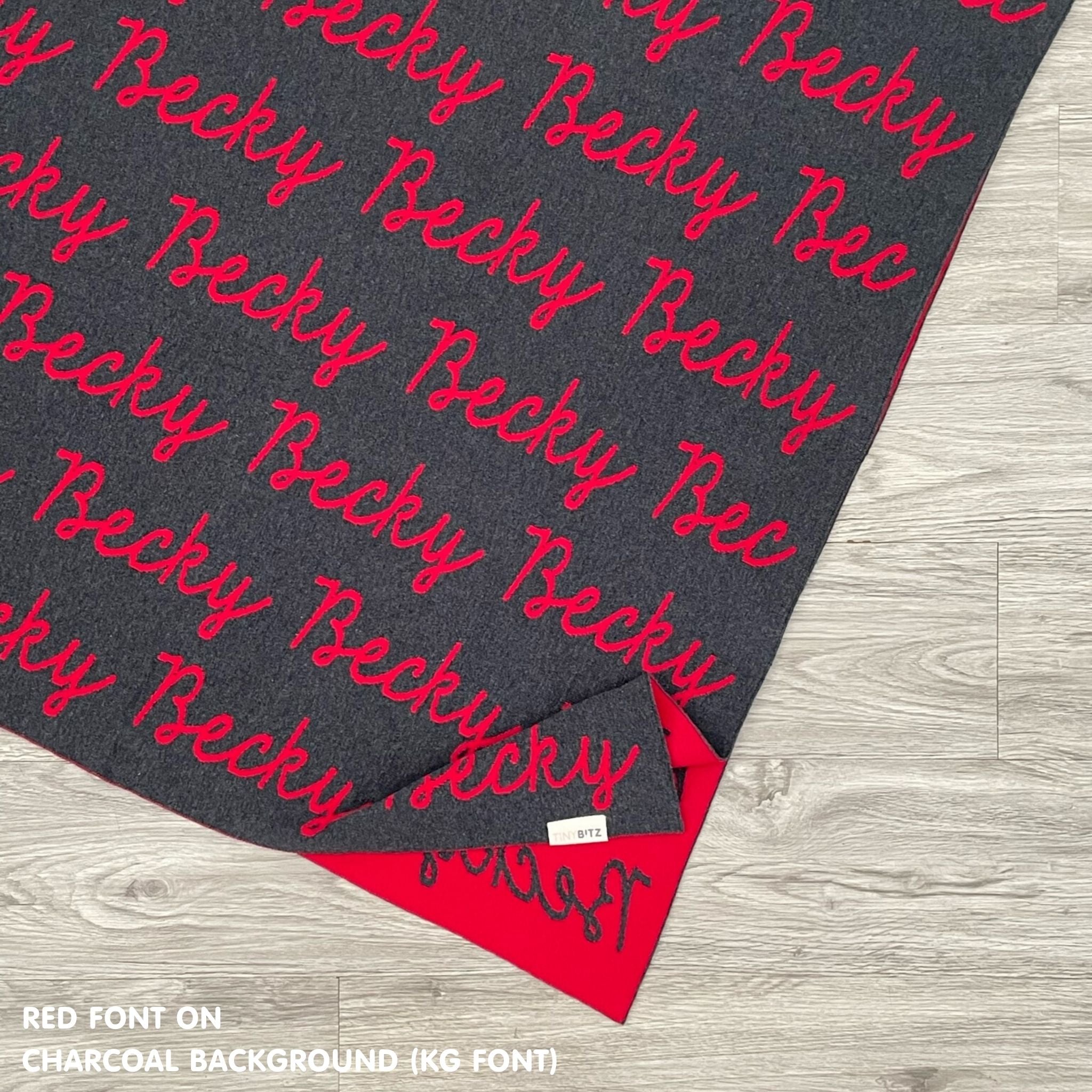 Personalised pet blanket in charcoal and red knitted cotton, custom dog blanket by TinyBitz, styled on modern wooden dog bed.