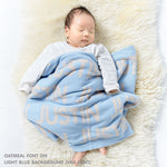 TinyBitz personalized knitted blanket in light blue background, customized with baby's name and made from 100% cotton.