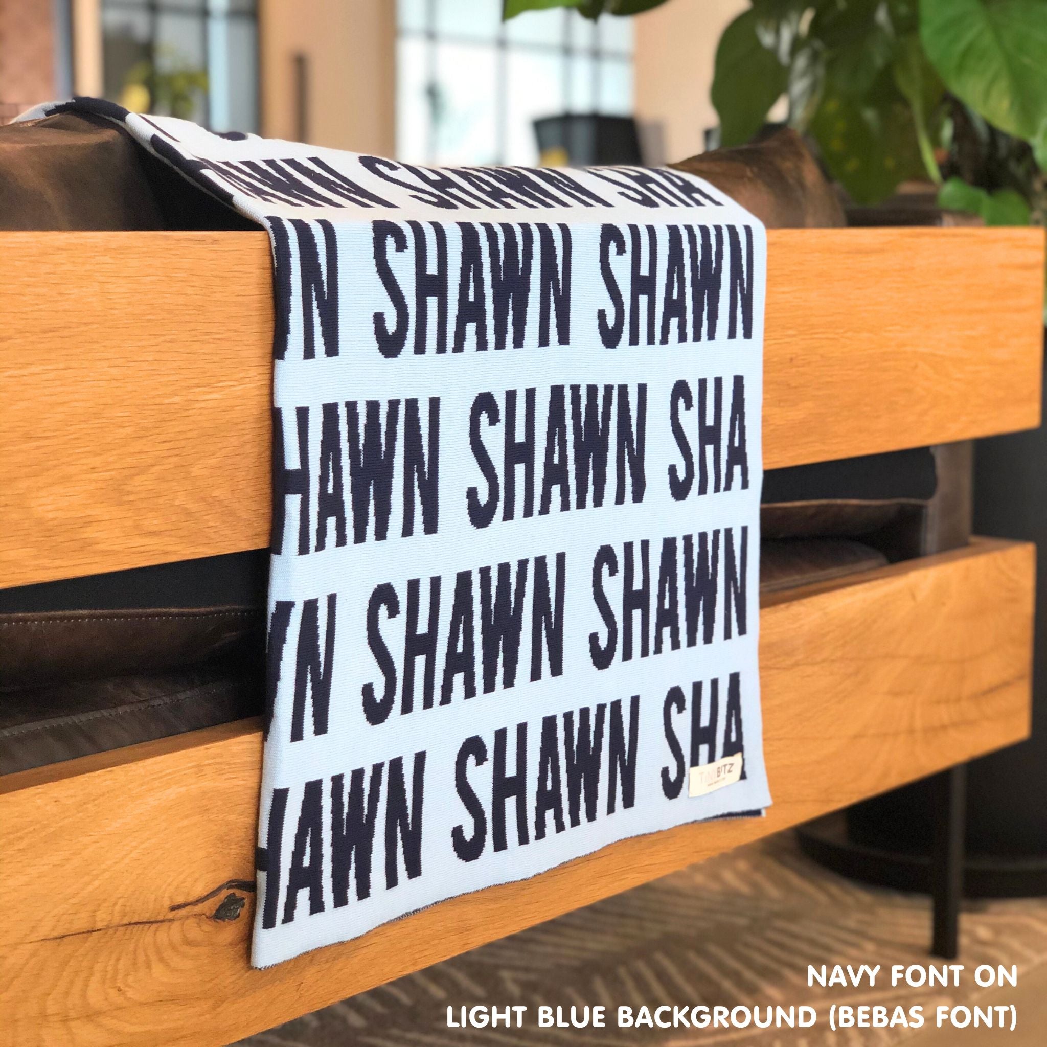 Custom name blanket in light blue and navy draped over a chair makes the best personalized home decor.