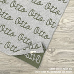 Customisable blanket with adult's name knitted in light grey and army green, personalized by TinyBitz.