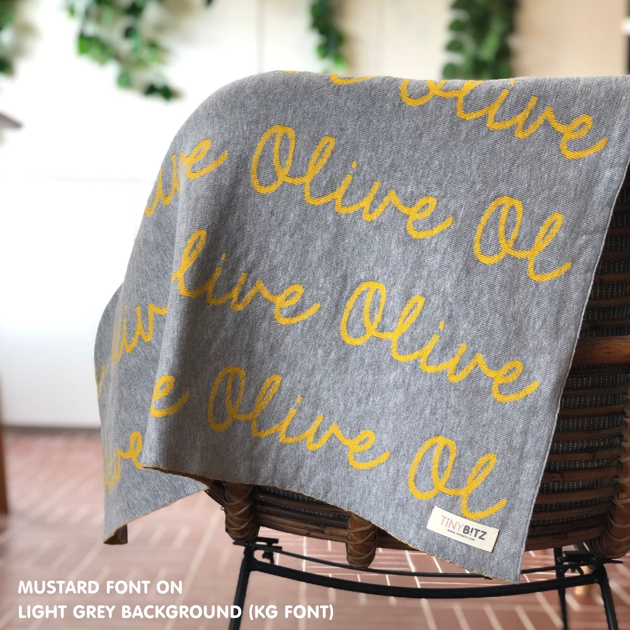 Custom name blanket in light grey and musatrd draped over a chair makes the best personalized home decor.