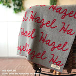 Customisable blanket with adult's name knitted in light grey and red, personalized by TinyBitz.
