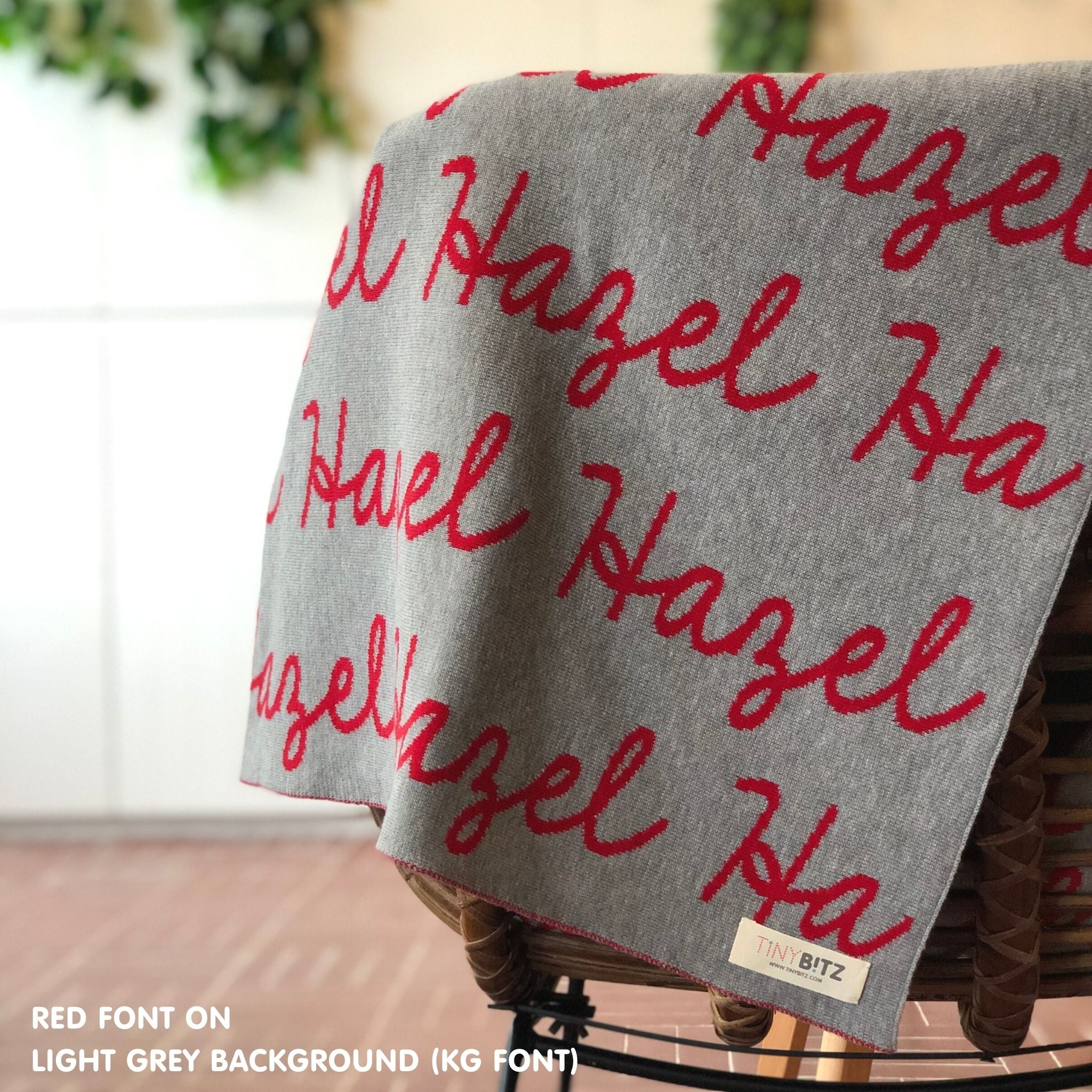 Customisable blanket with adult's name knitted in light grey and red, personalized by TinyBitz.