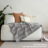 Custom name blanket draped on sofa, knitted in light grey and light pink makes the best personalised home decor.