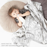 TinyBitz personalized knitted blanket in light grey background, customized with baby's name and made from 100% cotton.