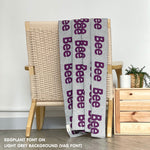 Custom name blanket in light grey and eggplant draped over a chair makes the best personalized home decor.