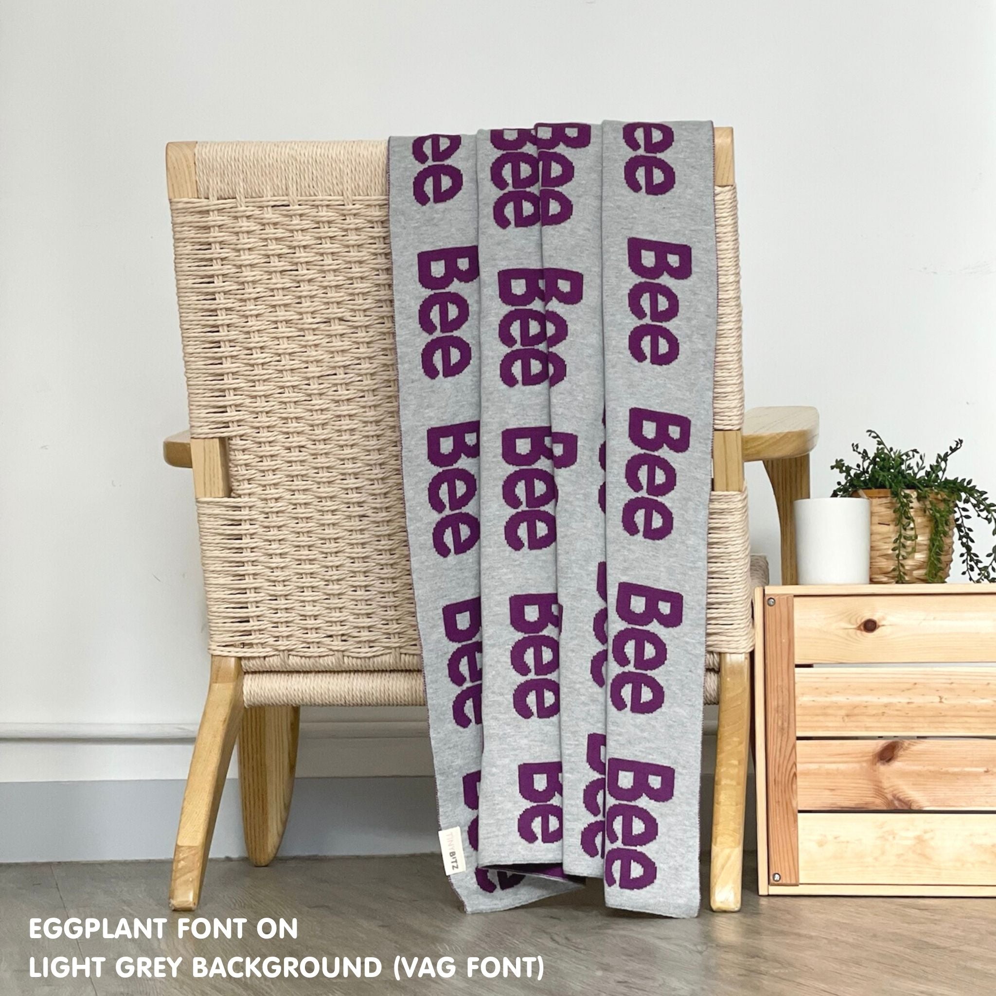 Custom name blanket in light grey and eggplant draped over a chair makes the best personalized home decor.