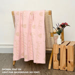 Personalized blanket with couple's name knitted in light pink and oatmeal, made by TinyBitz.