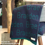 Custom name blanket in navy and teal draped over a chair makes the best personalized home decor.