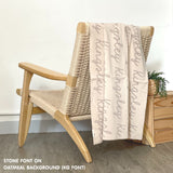 Custom name blanket in oatmeal and stone draped over a chair makes the best personalized home decor.