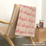 Personalized blanket with couple's name knitted in oatmeal and rose pink, made by TinyBitz.