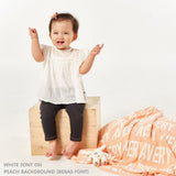 TinyBitz personalized knitted blanket in peach background, customized with baby's name and made from 100% cotton.