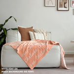 Custom name blanket draped on sofa, knitted in peach and white makes the best personalised home decor.