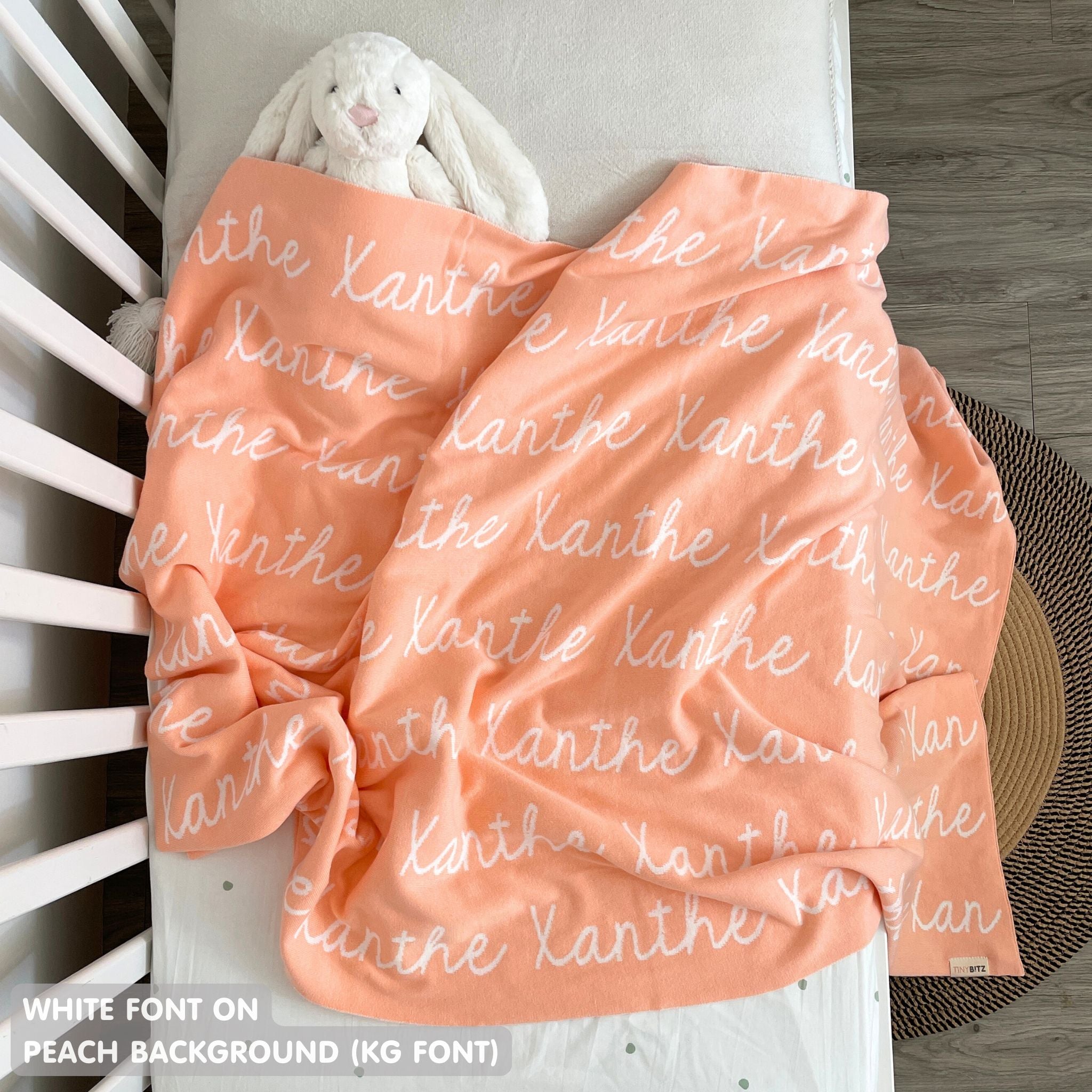 Knitted baby blanket in peach and white, customised with baby's name, made by TinyBitz.