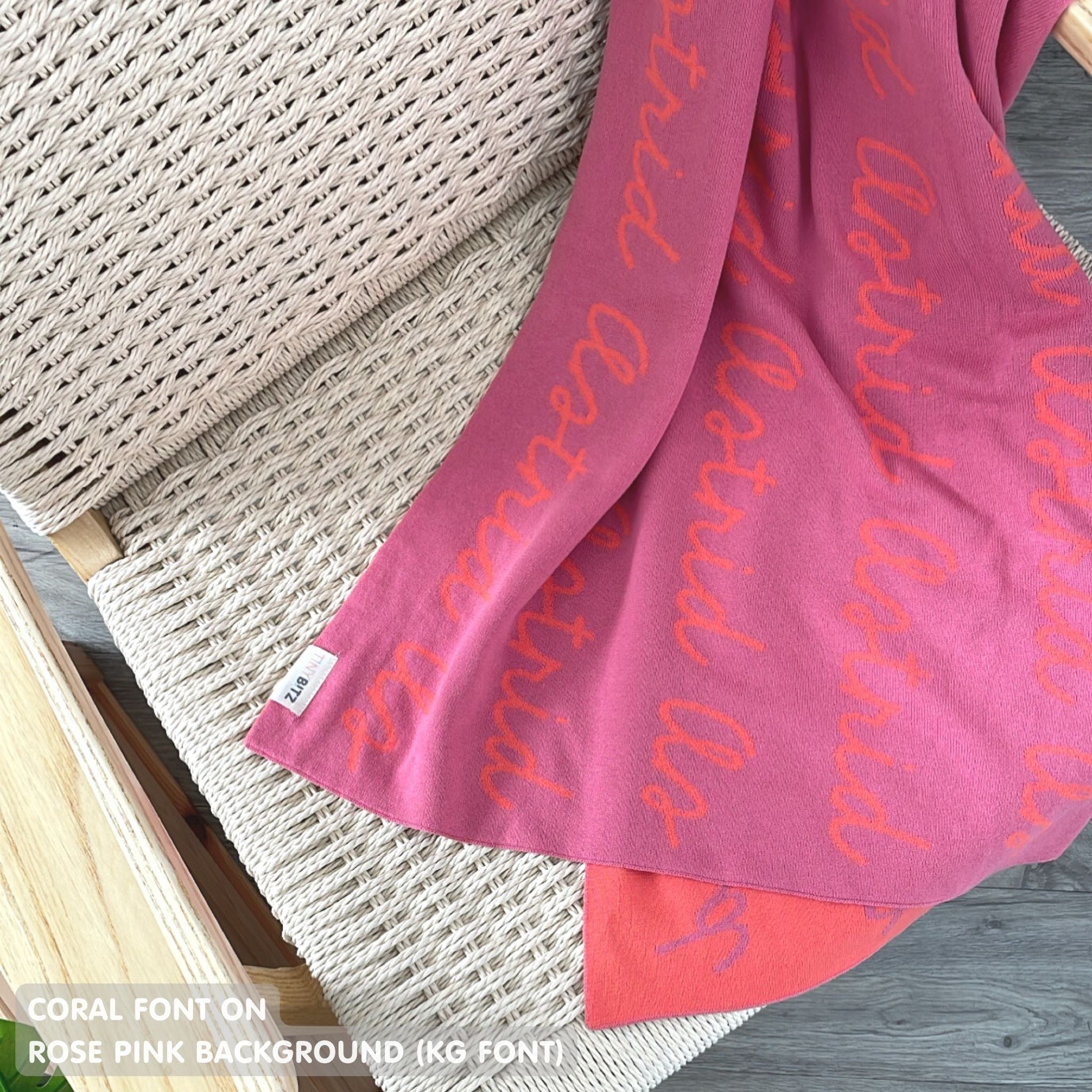 Customisable blanket with adult's name knitted in rose pink and coral, personalized by TinyBitz.