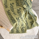Custom name blanket draped on chair, knitted in sage and army green makes the best personalised home decor.
