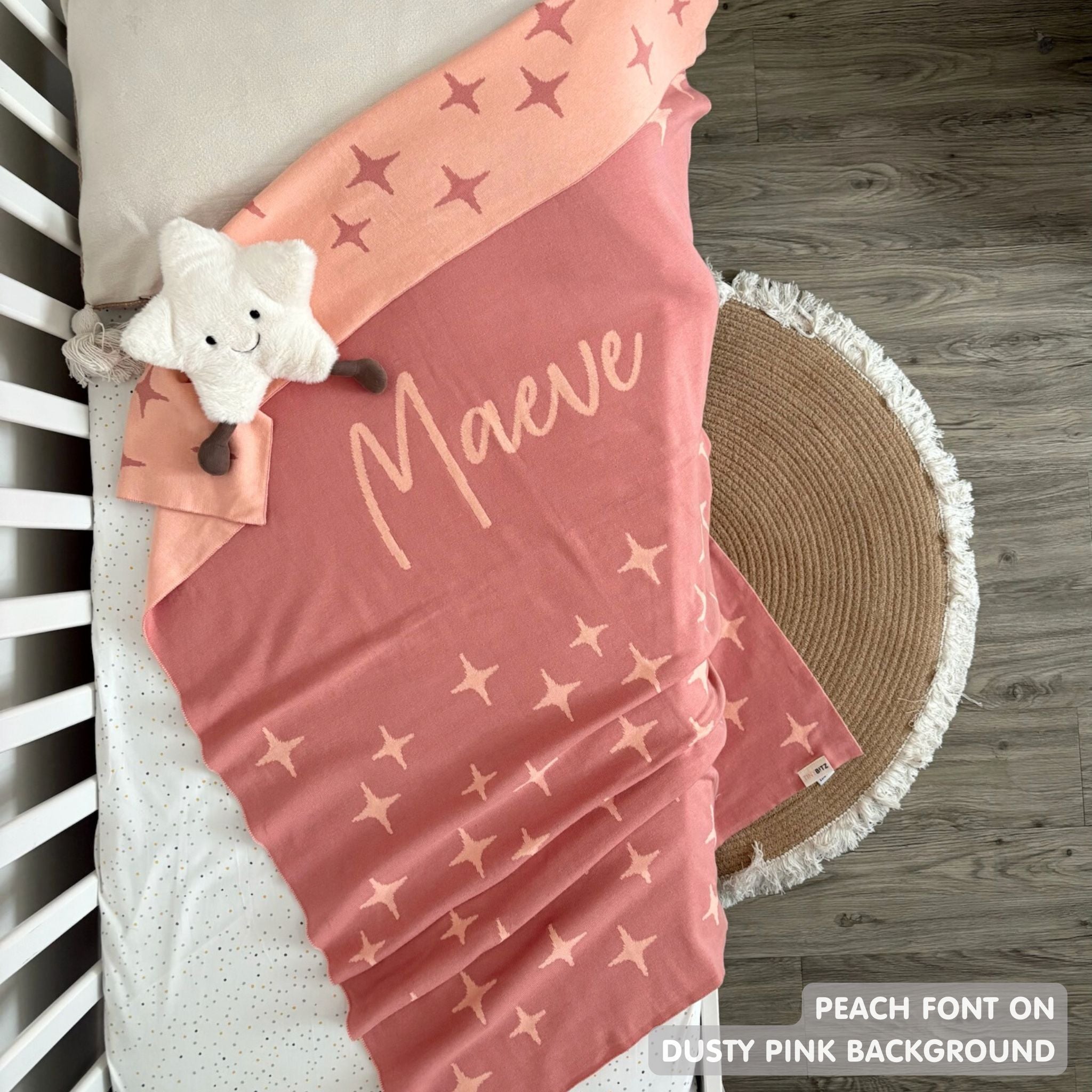 Knitted baby blanket in dusty pink and peach with a twinkles pattern, customised with baby's name, made by TinyBitz.