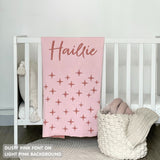 TinyBitz custom knitted blanket with baby's name on light pink background with a twinkles pattern, best gift to welcome a newborn baby.