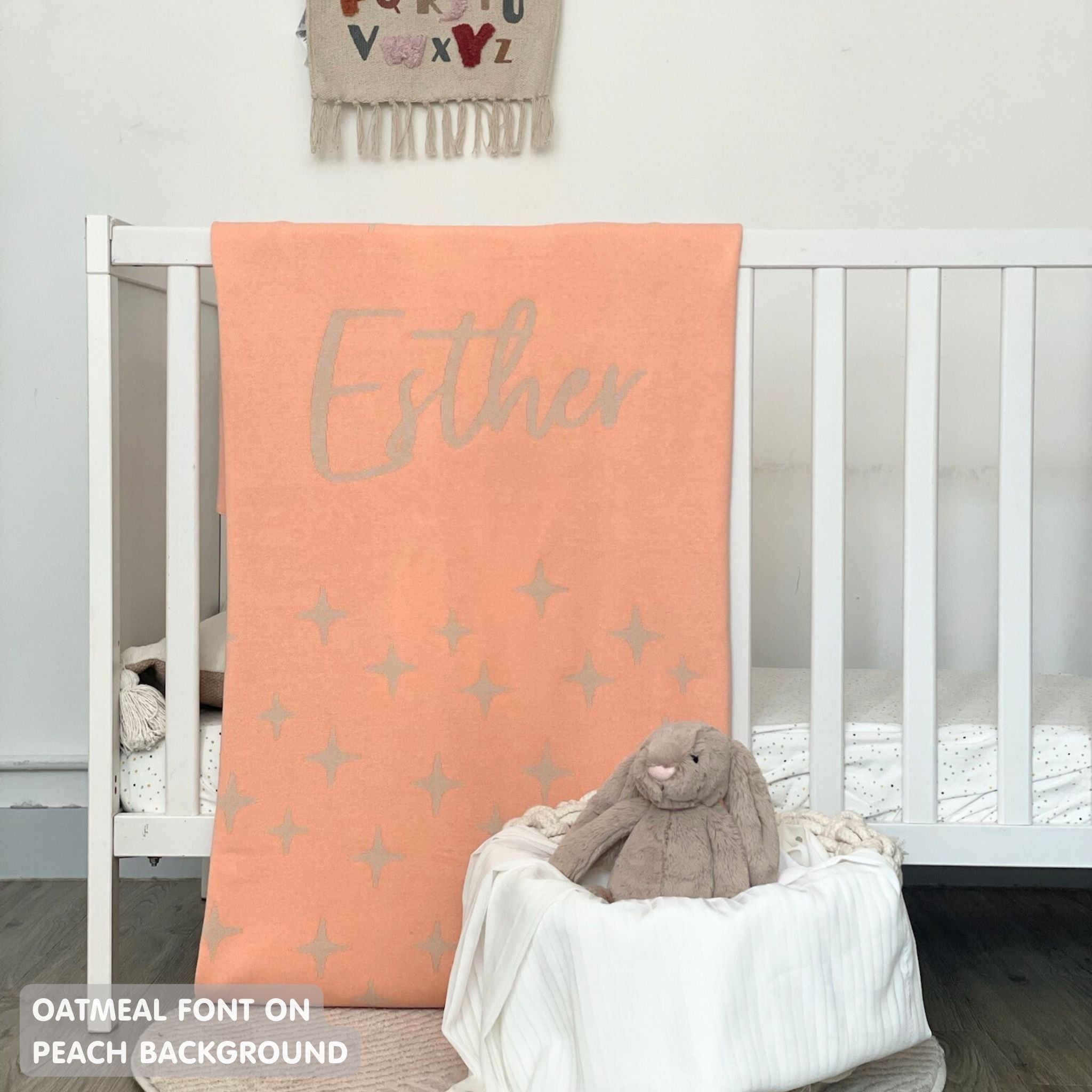 Baby blanket knitted from cotton personalized with baby's name in peach and oatmeal with a twinkles pattern, made by TinyBitz.