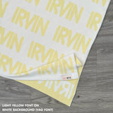 Customisable blanket with adult's name knitted in white and light yellow, personalized by TinyBitz.