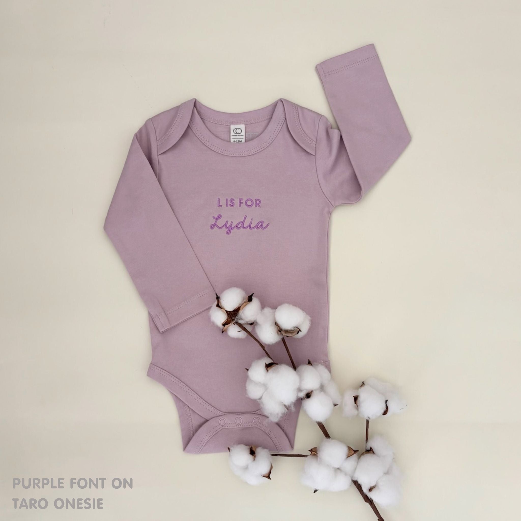 Neutral-tone personalised baby onesie featuring custom name, made-to-order newborn gift by TinyBitz.