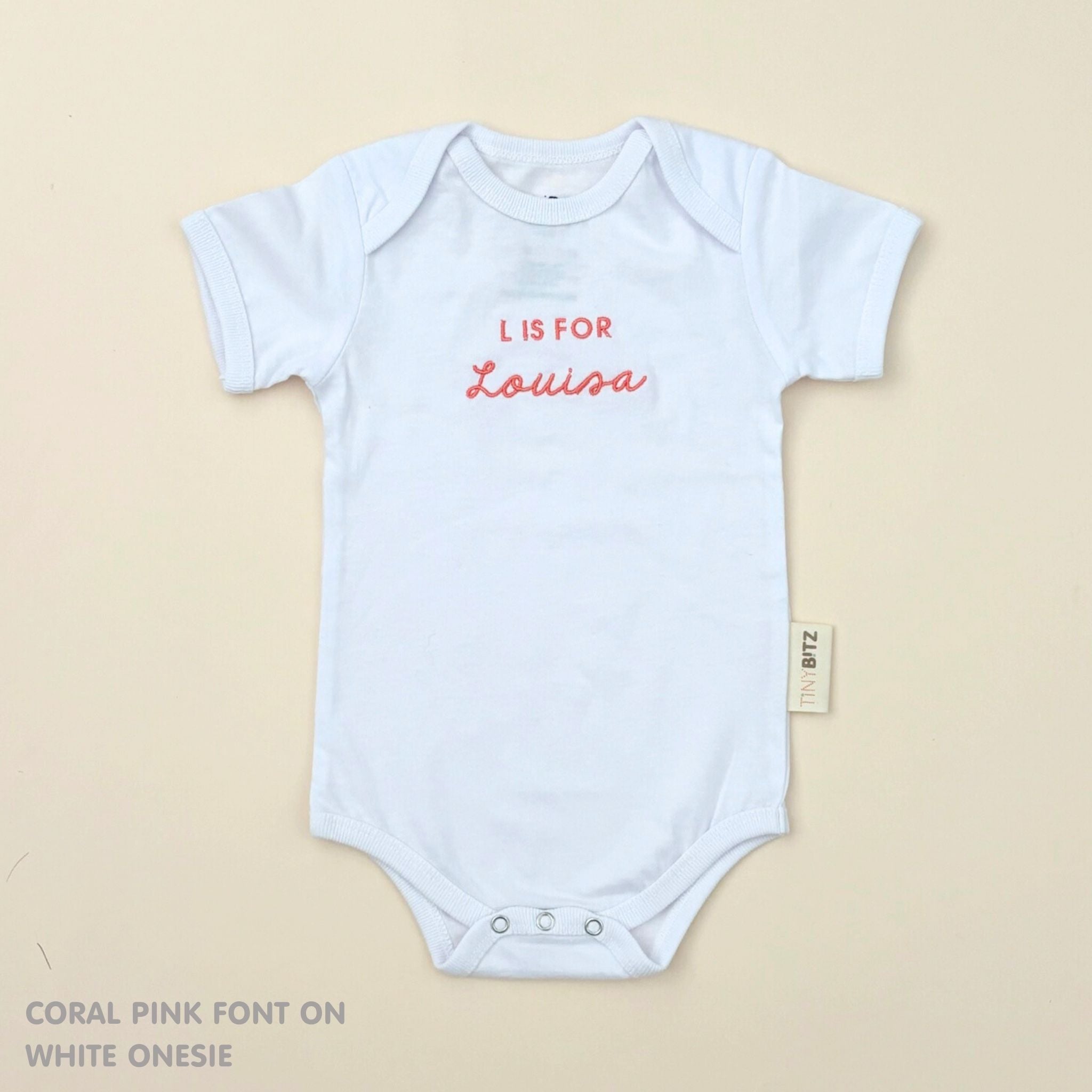 TinyBitz Personalised baby onesie with embroidered name in soft white cotton, perfect for birth announcements and newborn photos.