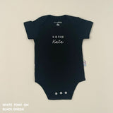 Organic cotton baby onesie with custom name, ideal for birth announcements, baby shower gifts, and keepsakes by TinyBitz.