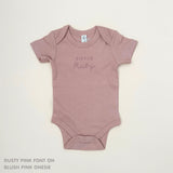 TinyBitz Personalised baby onesie with embroidered name in soft blush pink cotton, perfect for birth announcements and newborn photos.