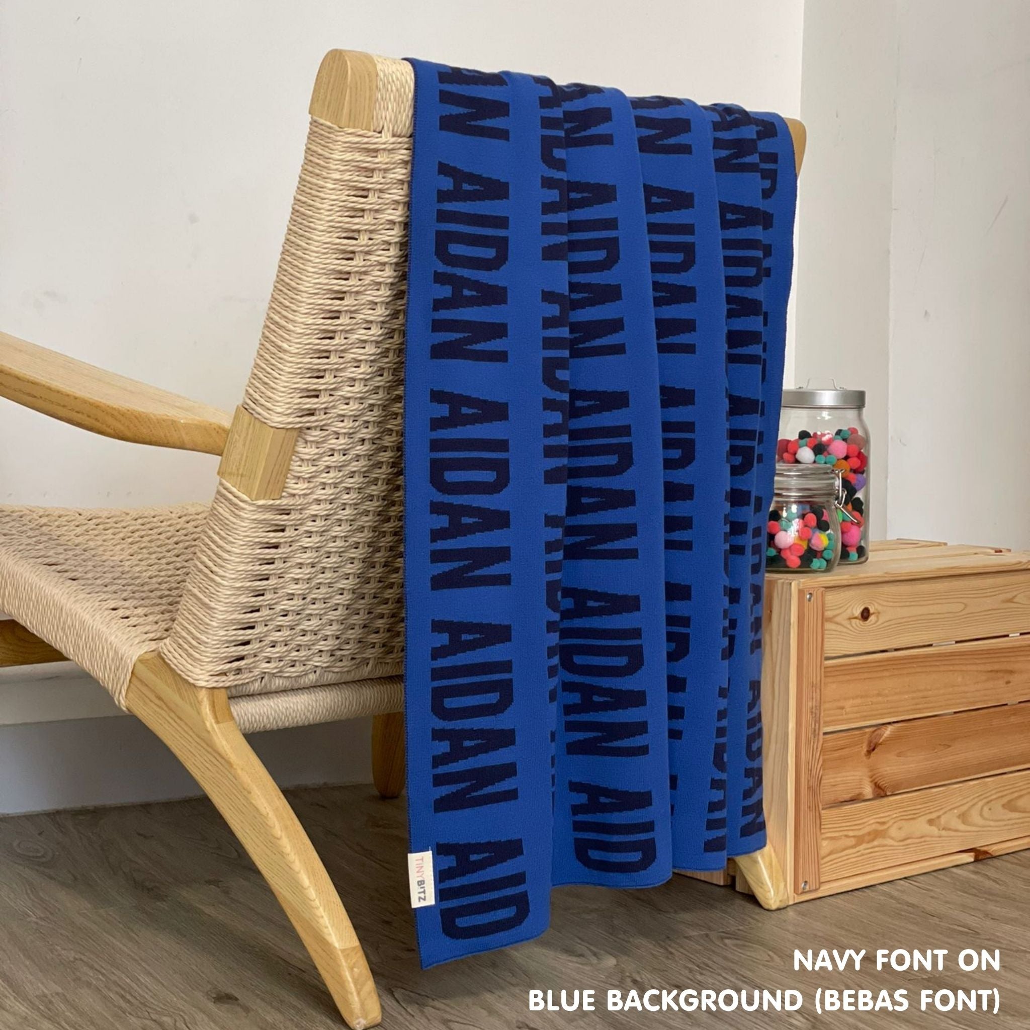 Personalised pet blanket in blue and navy knitted cotton, custom dog blanket by TinyBitz, styled on modern wooden dog bed.