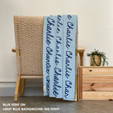 Personalised pet blanket in light blue and blue knitted cotton, custom dog blanket by TinyBitz, styled on modern wooden dog bed.